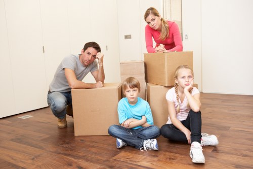 Movers organizing labeled boxes during packing services in Bow